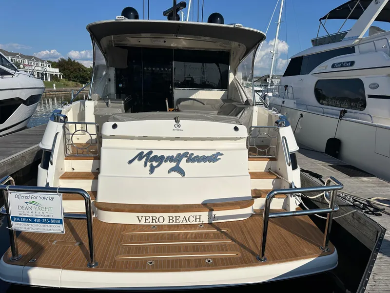 Slide: The Image of 2022 Riviera Sport Yacht 5400 Platinum Edition docked, rear view with "Magnificent" nameplate. - 29