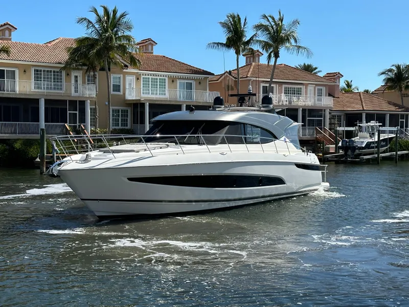 Slide: The Image of 2022 Riviera Sport Yacht 5400 Platinum Edition cruising near waterfront homes. - 3