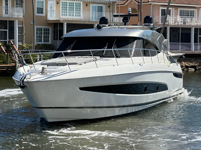 Slide: The Image of 2022 Riviera Sport Yacht 5400 Platinum Edition cruising near waterfront homes. - 4