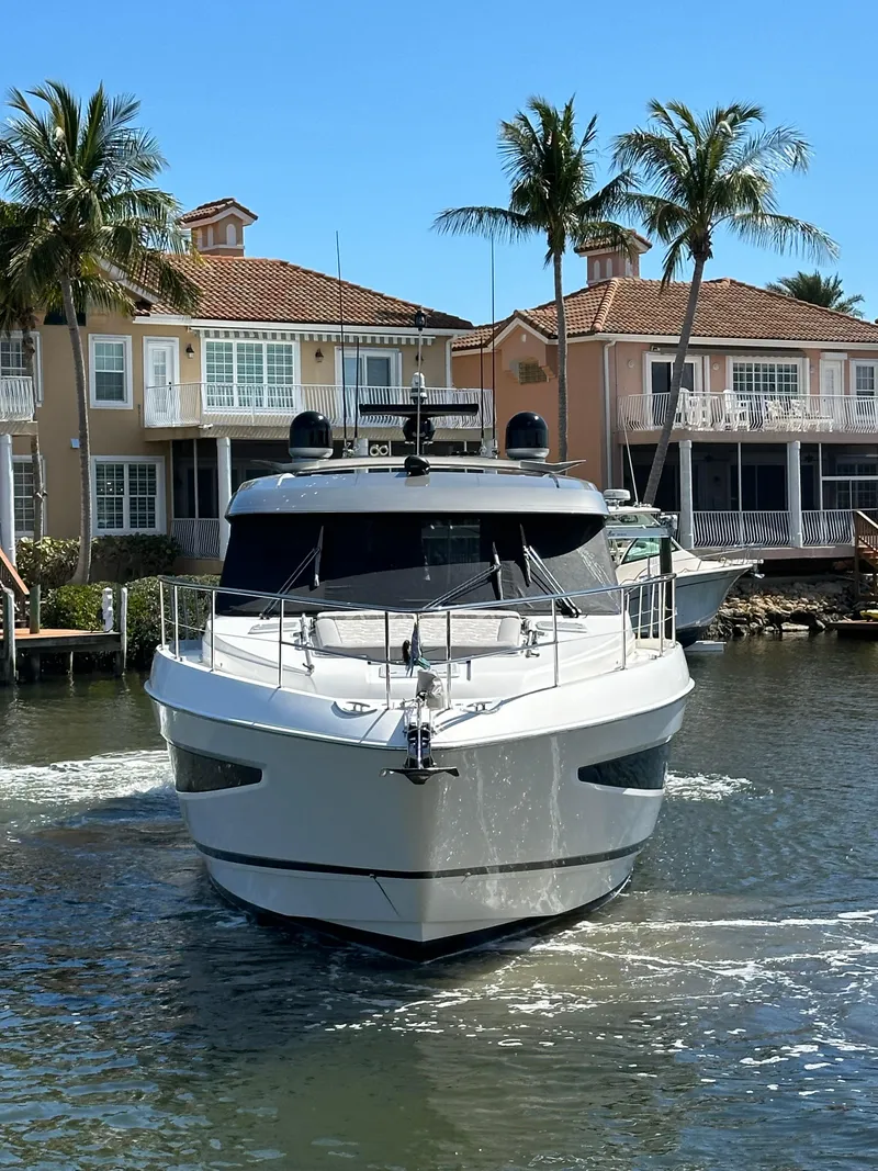 Slide: The Image of 2022 Riviera Sport Yacht 5400 Platinum Edition cruising near waterfront homes. - 5