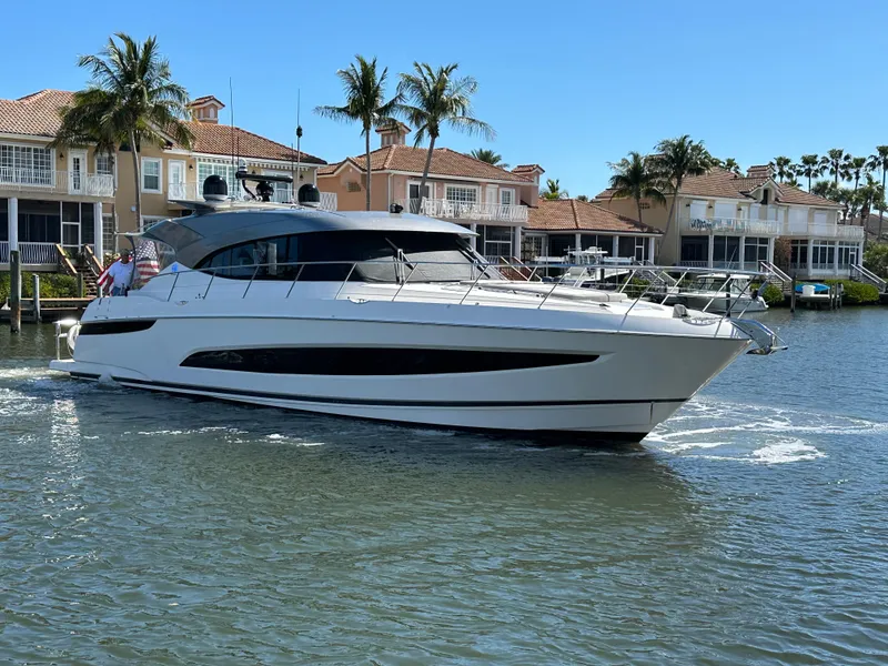 Slide: The Image of 2022 Riviera Sport Yacht 5400 Platinum Edition cruising near waterfront homes. - 6