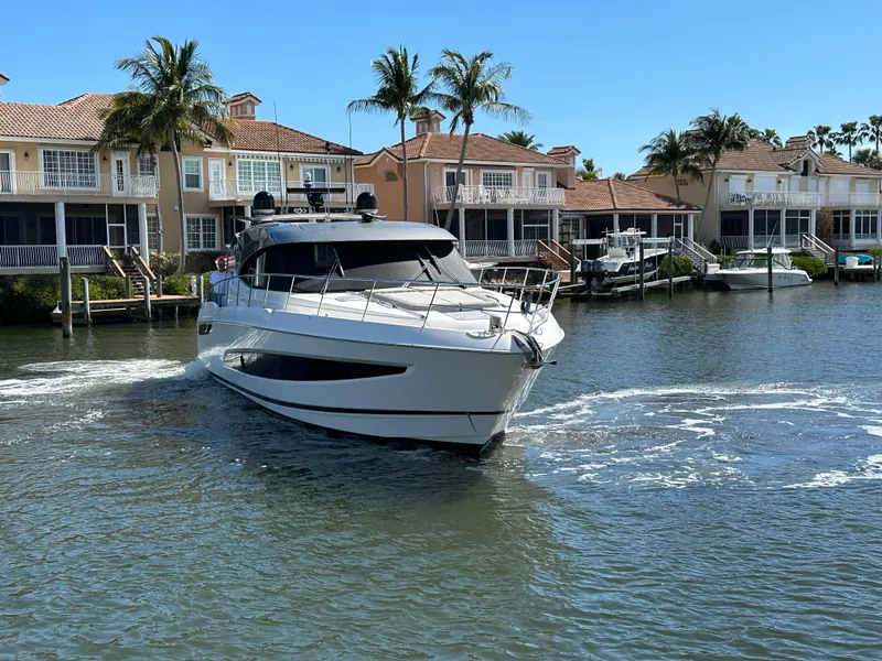 Slide: The Image of 2022 Riviera Sport Yacht 5400 Platinum Edition cruising near waterfront homes. - 7