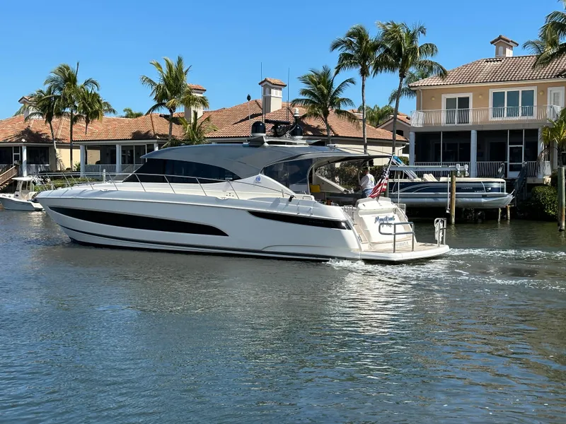 Slide: The Image of 2022 Riviera Sport Yacht 5400 Platinum Edition cruising near waterfront homes. - 8