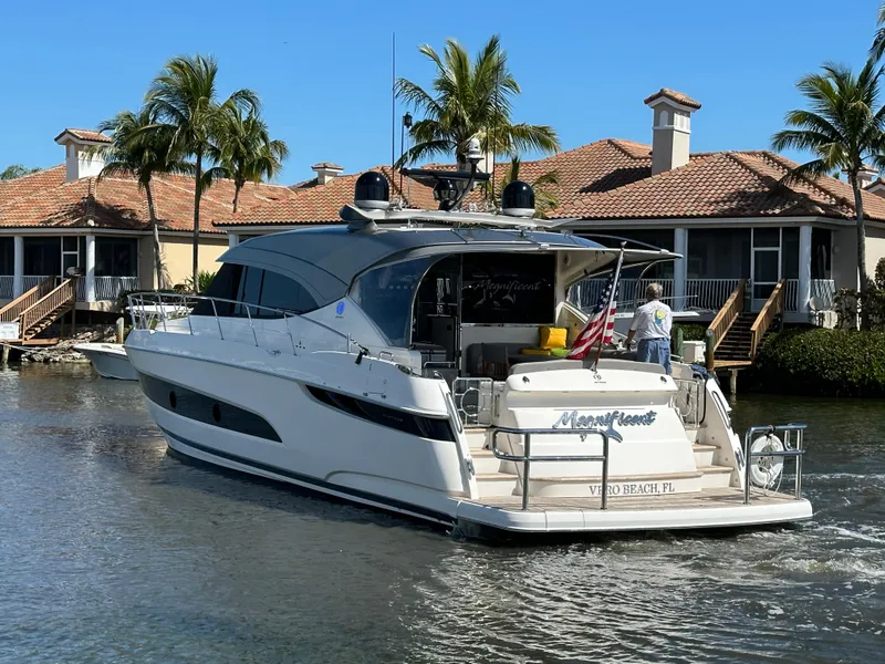 Slide: The Image of 2022 Riviera Sport Yacht 5400 Platinum Edition cruising near waterfront homes. - 9