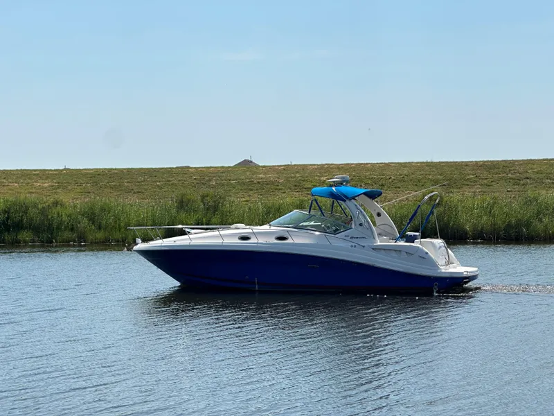 The Image of 2006 Sea Ray 340 Sundancer cruising on a calm lake under a clear blue sky. - 0