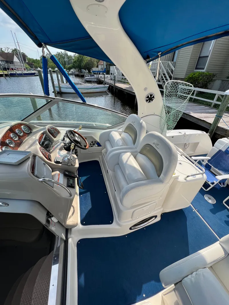 Slide: The Image of 2006 Sea Ray 340 Sundancer cockpit with blue canopy, dual seats, and marina view. - 10