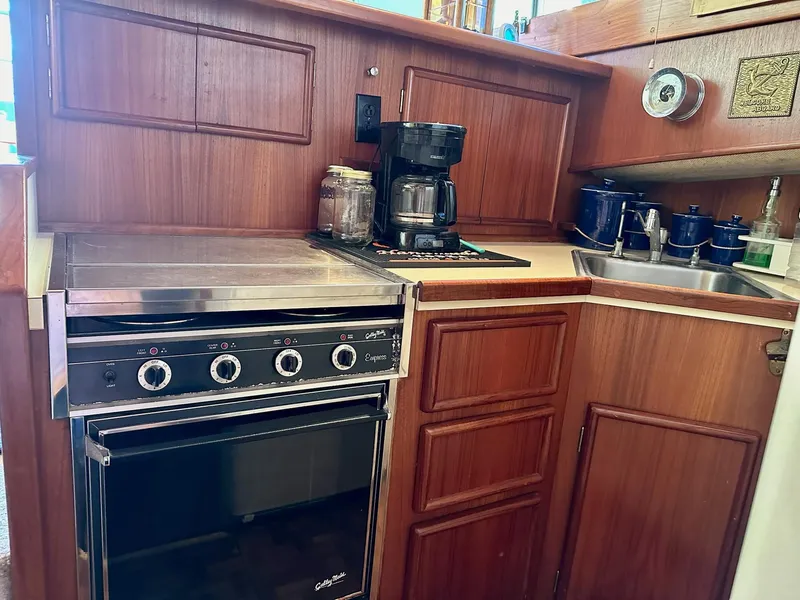 Slide: The Image of 1987 Post 46 SPORT yacht kitchen with stove, coffee maker, and wooden cabinetry. - 16