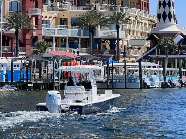 Slide: The Image of 2024 Sea Fox 251 Bay Fox boat cruising near a vibrant waterfront with buildings and palm trees. - 15