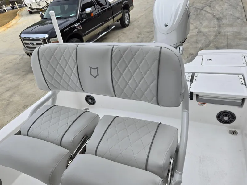 Slide: The Image of 2024 Sea Fox 251 Bay Fox boat with cushioned seating and outboard motor. - 9