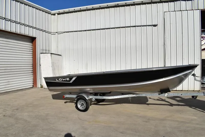 Slide: The Image of 2024 Lowe WV 1670 boat on a trailer outside a metal building. - 3