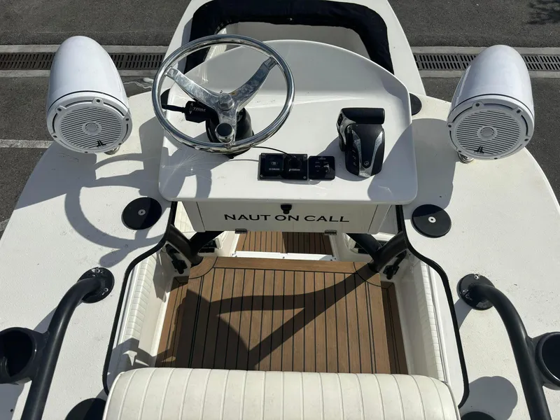 Slide: The Image of 2014 Andros Tarpon 26 boat helm with steering wheel, controls, and speakers. - 19