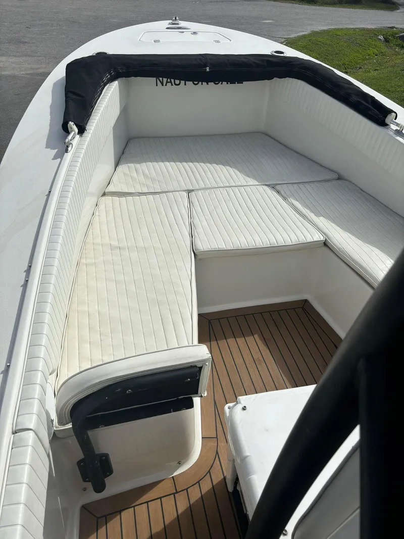 Slide: The Image of 2014 Andros Tarpon 26 boat with white cushioned seating and wooden deck. - 8