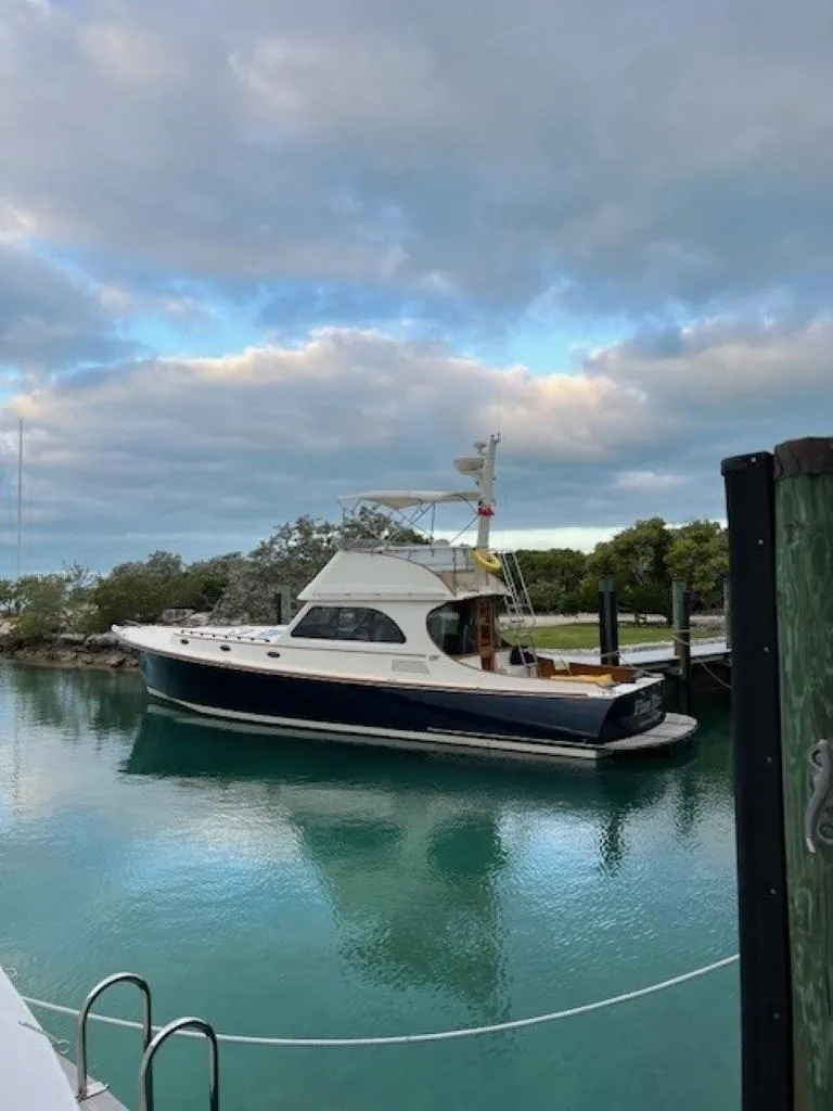 The Image of 2002 Hinckley Talaria 44 FB yacht docked in serene waters under a cloudy sky. - 0