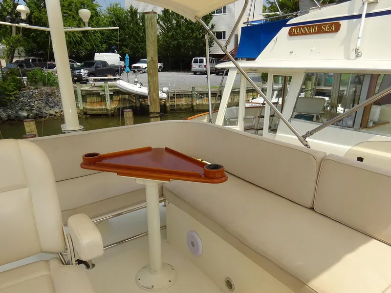 Slide: The Image of Hinckley Talaria 44 FB 2002 yacht interior with cushioned seating and triangular wooden table. - 12