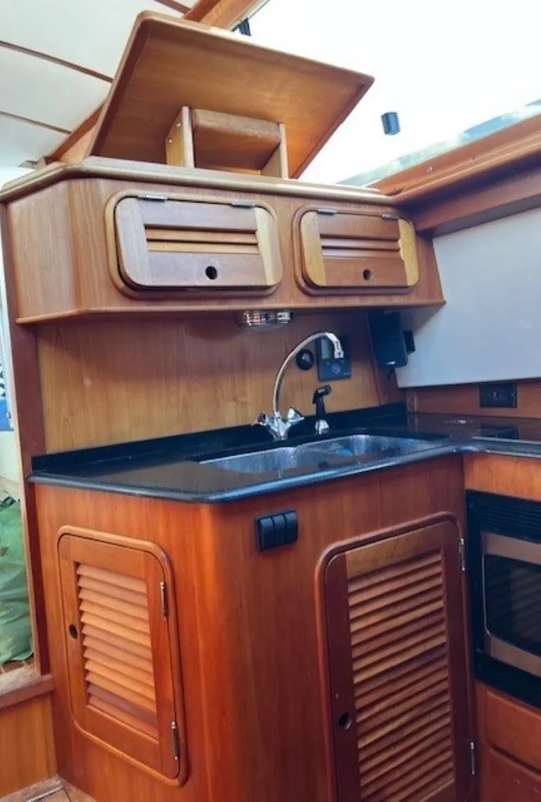 Slide: The Image of 2002 Hinckley Talaria 44 FB yacht kitchen with wooden cabinetry and sink. - 21