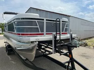 The Image of 2024 Sweetwater 2286C pontoon boat on a trailer, parked outdoors. - 0