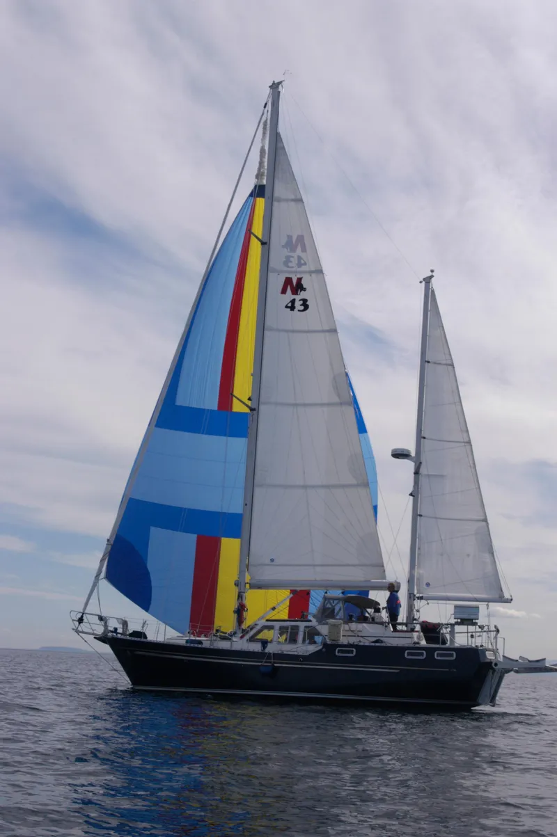 Slide: The Image of Sailing yacht Nauticat 43, 1985 model, with colorful sails on open water. - 0