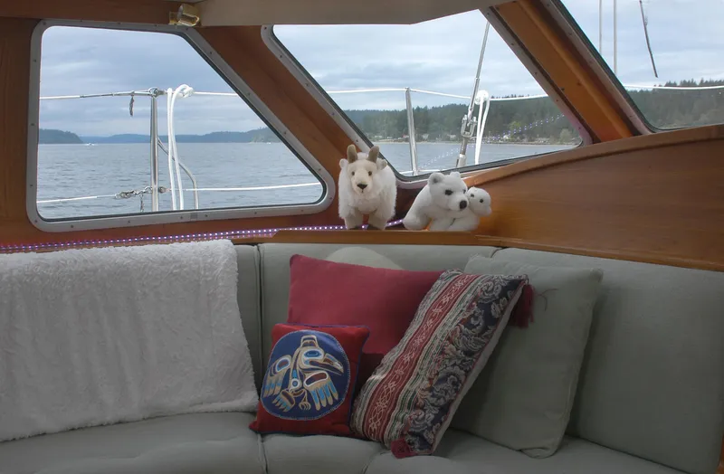 Slide: The Image of Cozy Nauticat 43 yacht interior with plush toys and decorative pillows, overlooking serene waters. - 3