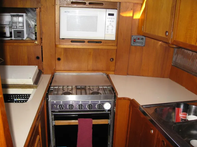Slide: The Image of 1985 Nauticat 43 yacht kitchen with stove, microwave, and wooden cabinetry. - 8
