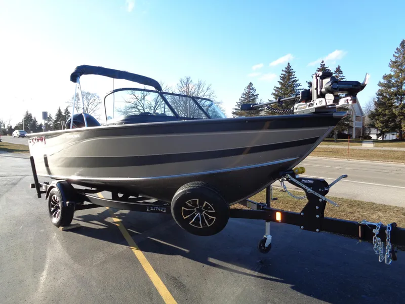 Slide: The Image of 2024 Lund 1875 Fisherman boat on trailer, parked outdoors under clear sky. - 2