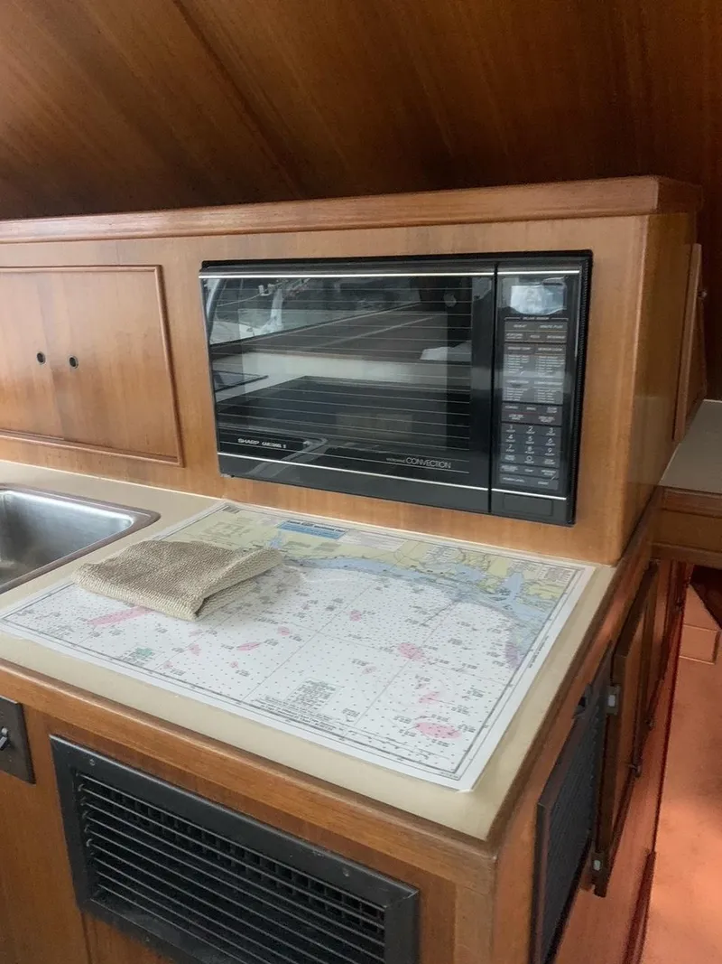 Slide: The Image of 1974 Hatteras 46 Convertible kitchen with microwave, sink, and nautical chart. - 14