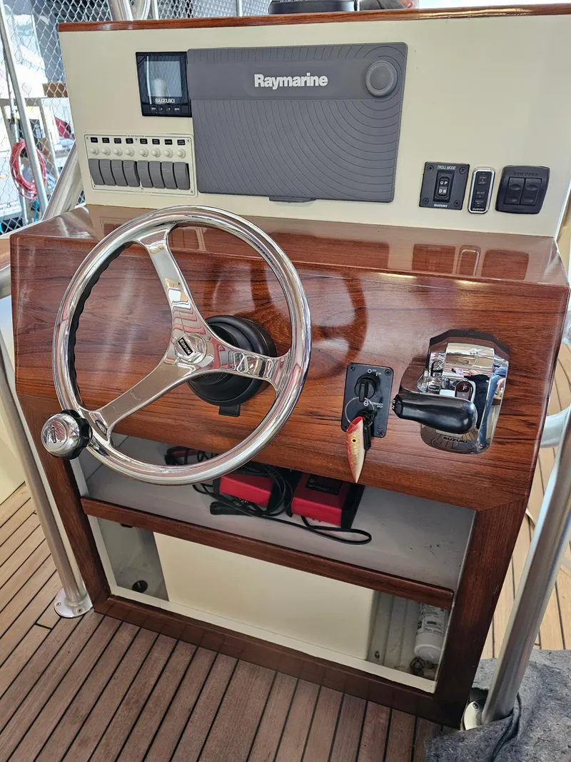 Slide: The Image of 2014 Custom 24' Center Console boat helm with Raymarine electronics and wooden dashboard. - 14