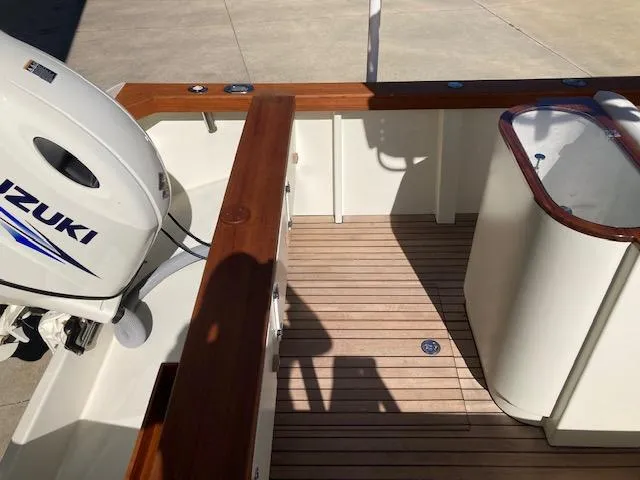 Slide: The Image of 2014 Custom 24' Center Console boat with Suzuki outboard motor, wooden deck, and sleek design. - 2