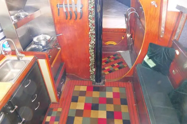 Slide: The Image of 1976 Choate Custom 38 yacht interior with colorful rug and compact kitchen area. - 10
