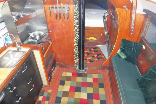 Slide: The Image of Interior of 1976 Choate Custom 38 sailboat with kitchen, seating, and colorful rugs. - 11