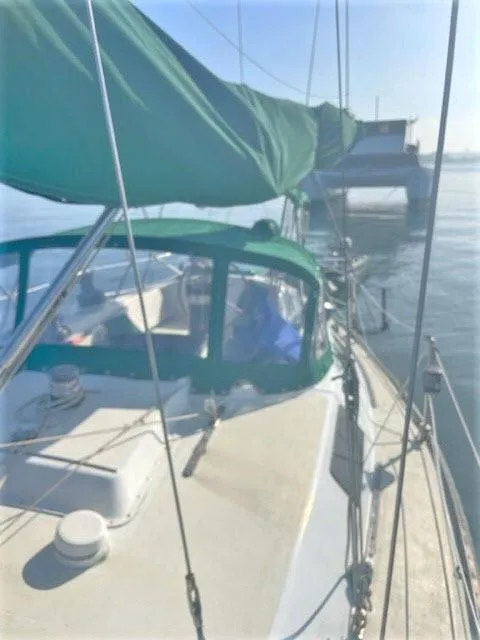 Slide: The Image of 1976 Choate Custom 38 sailboat with green canopy docked in calm waters. - 43