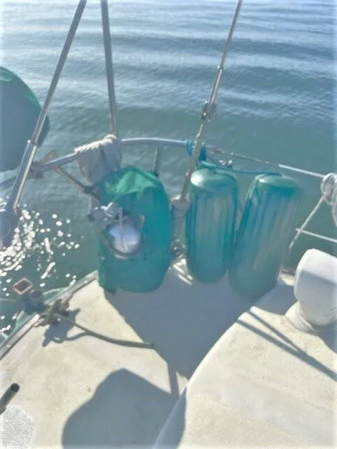 Slide: The Image of 1976 Choate Custom 38 sailboat deck with green fenders on calm water. - 44