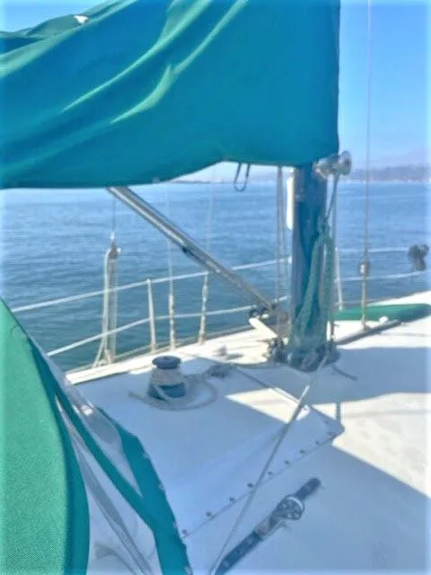 Slide: The Image of 1976 Choate Custom 38 sailboat deck with green sail cover on calm water. - 46