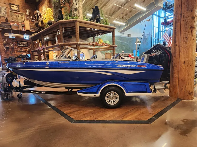 Slide: The Image of 2024 Ranger 1880MS blue boat on display indoors with trailer. - 1