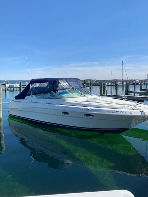 Slide: The Image of 1997 Cruisers Yachts 3120 Aria docked, blue canopy, calm waters. - 3
