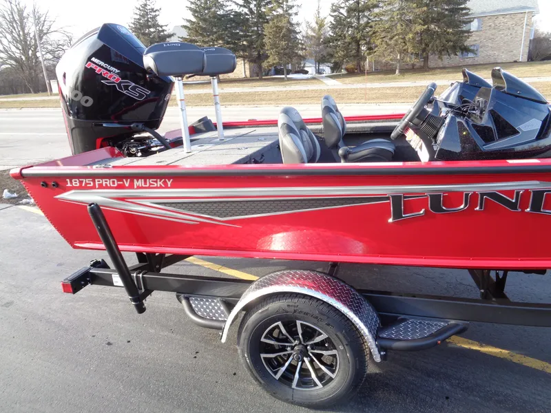 Slide: The Image of 2024 Lund 1875 Pro-V Bass boat in red, side view on trailer. - 2
