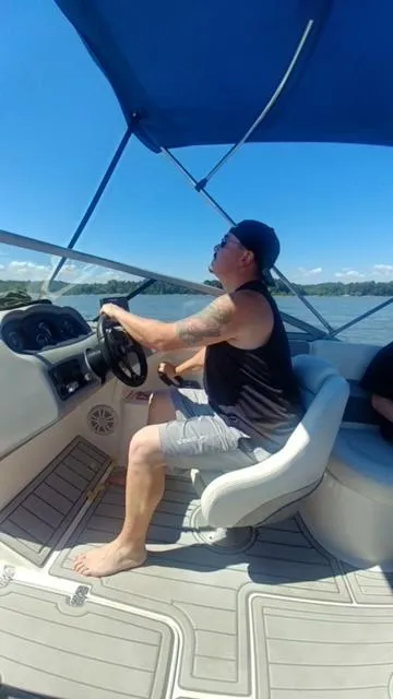 Slide: The Image of Man steering a 2006 Yamaha SX 230 boat under a blue canopy on a sunny day. - 34