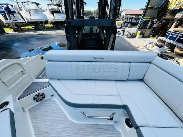 Slide: The Image of 2024 Sea Ray 270 SDX boat interior with white seating and docked boats in background. - 14