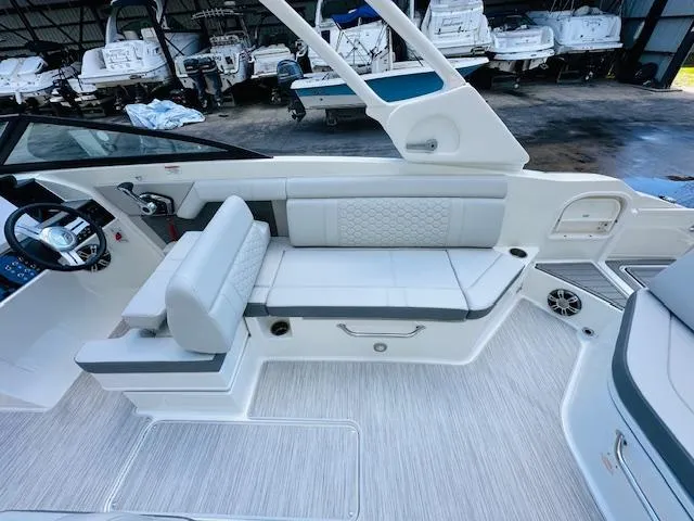 Slide: The Image of 2024 Sea Ray 270 SDX interior seating and helm station in a boat storage facility. - 16
