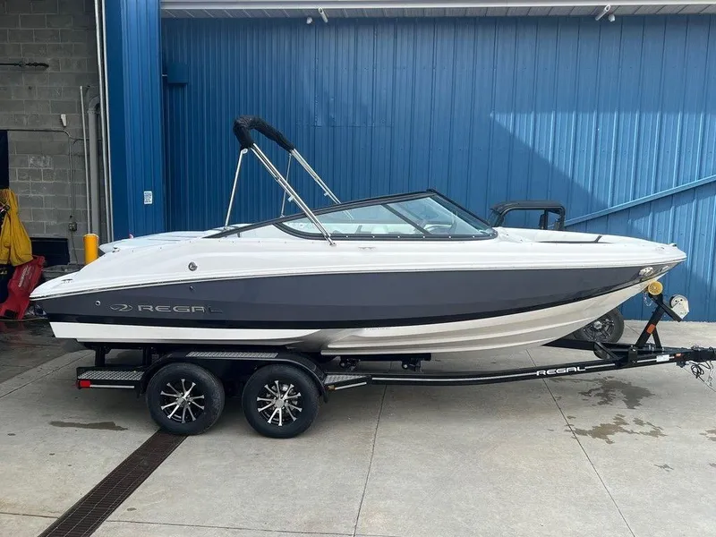 Slide: The Image of 2024 Regal 2000 ES boat on trailer, parked outside a blue building. - 17