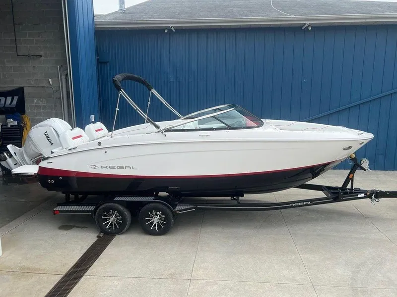 Slide: The Image of 2024 Regal LX4 boat on trailer in front of blue building. - 19