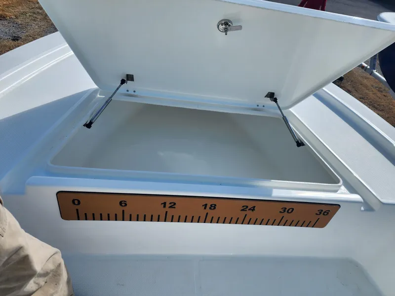 Slide: The Image of 2024 Savannah 220 IS boat storage compartment with open lid and measuring scale. - 20