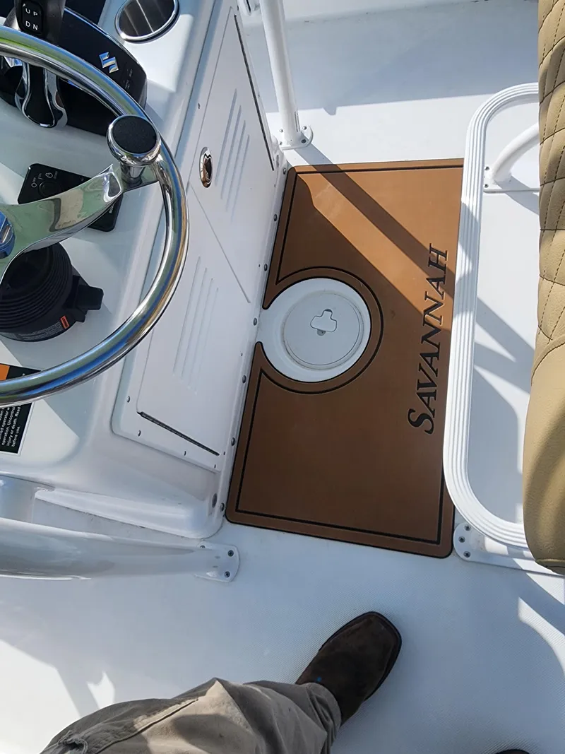 Slide: The Image of 2024 Savannah 220 IS boat interior with steering wheel and branded mat. - 25