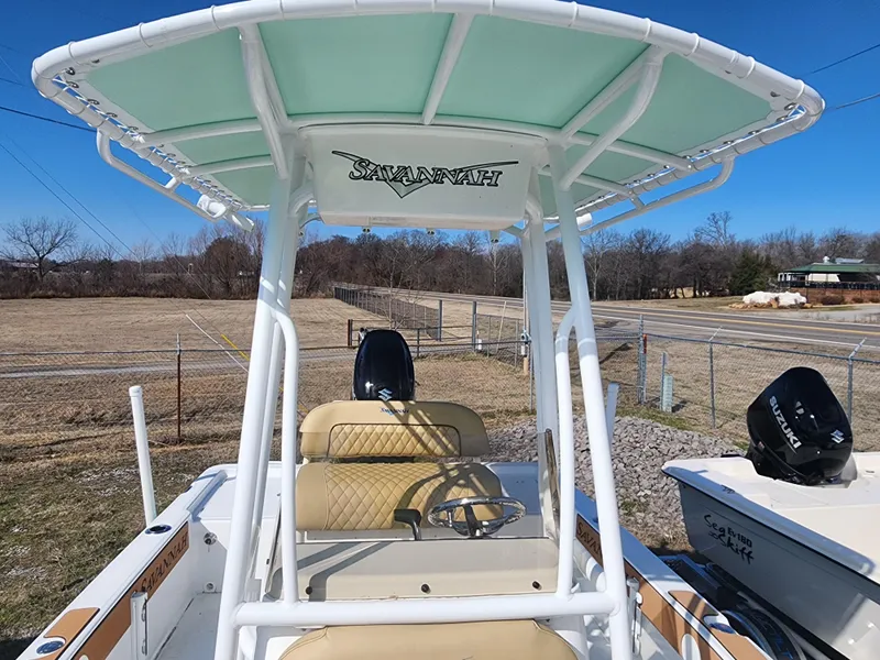 Slide: The Image of 2024 Savannah 220 IS boat with T-top and seating, parked outdoors. - 28