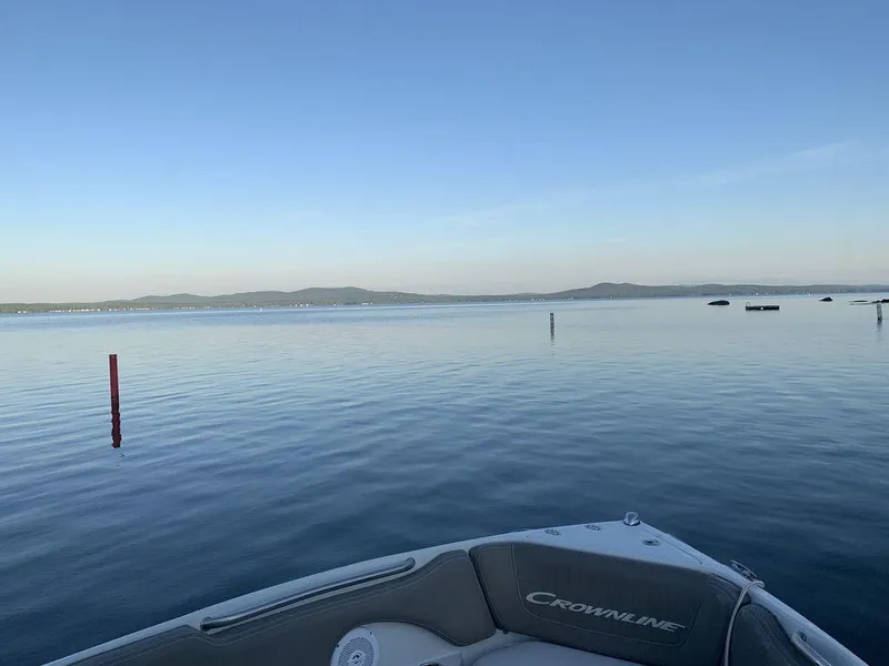 Slide: The Image of Crownline 215 SS boat on calm lake with distant hills, 2020 model. - 8