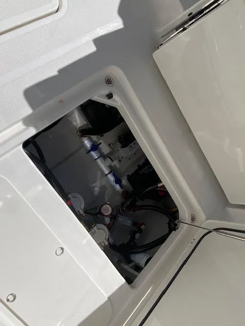 Slide: The Image of 2024 Pursuit S 268 boat interior compartment with visible wiring and plumbing. - 13
