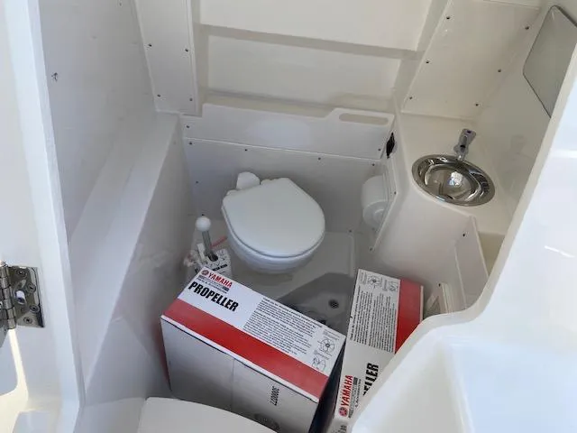Slide: The Image of 2024 Pursuit S 268 boat interior with toilet, sink, and Yamaha propeller boxes. - 22