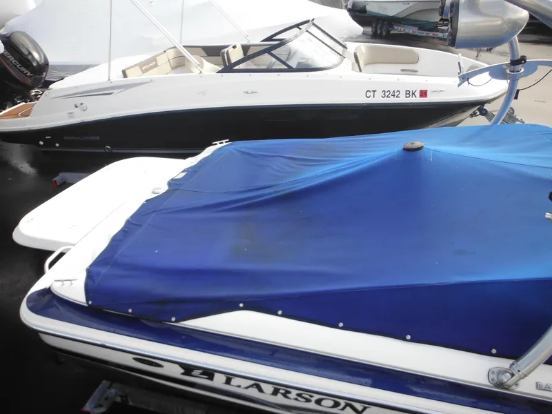 Slide: The Image of 2006 Larson SEi 180 Sport I/O boat with blue cover, docked beside another boat. - 18
