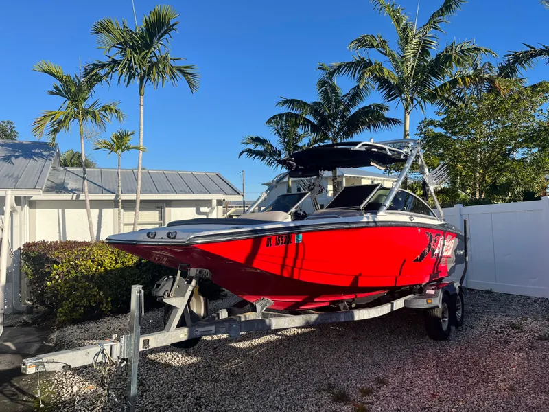 Slide: The Image of 2009 MasterCraft MariStar 230 boat on trailer, parked in a tropical setting. - 9