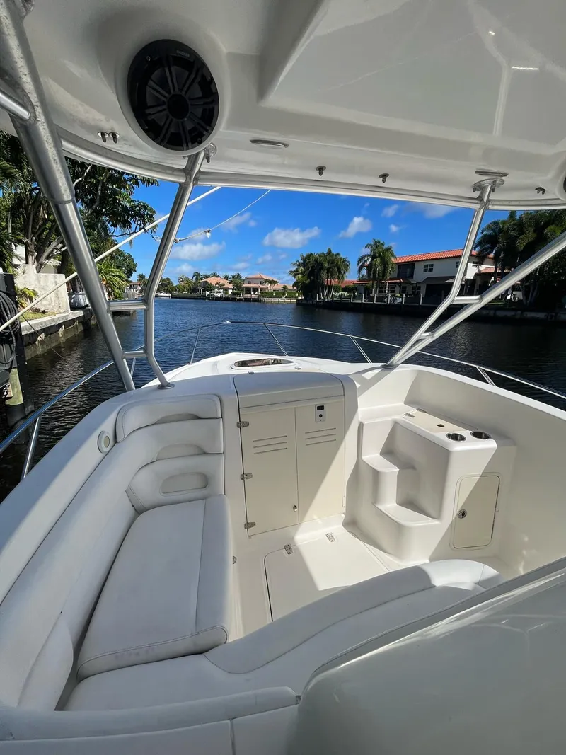 Slide: The Image of 2006 Boston Whaler 320 Outrage Cuddy Cabin interior with seating, docked by a scenic waterfront. - 6