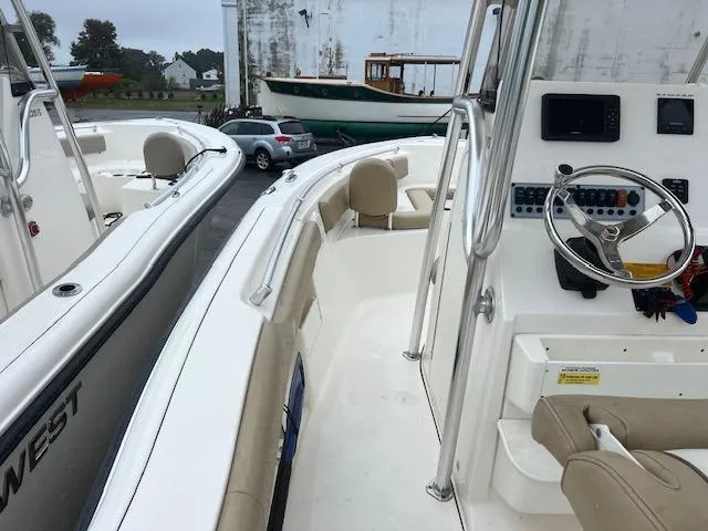 Slide: The Image of 2020 Key West 239 FS boat interior with steering wheel and seating, docked near other boats. - 4